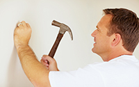 worker hammering nail into wall